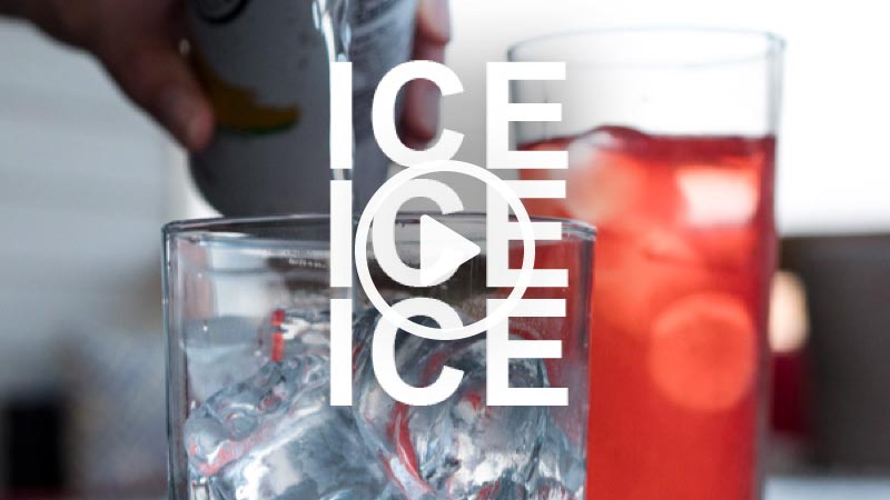 A closeup of a hand pouring a can of seltzer over a glass of ice.